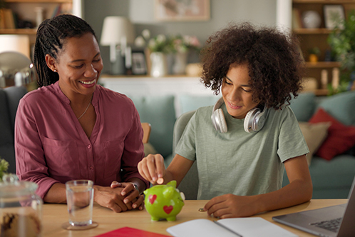 Forfamilies Financialeducation mom and daughter putting money in piggy bank